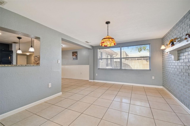 unfurnished dining area with brick wall and light tile patterned flooring