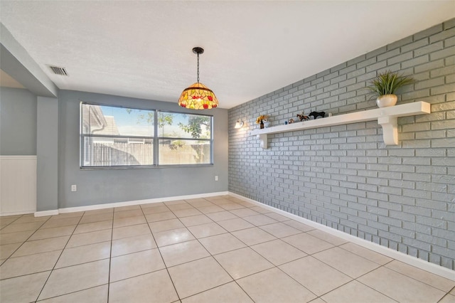 unfurnished dining area with light tile patterned floors and brick wall