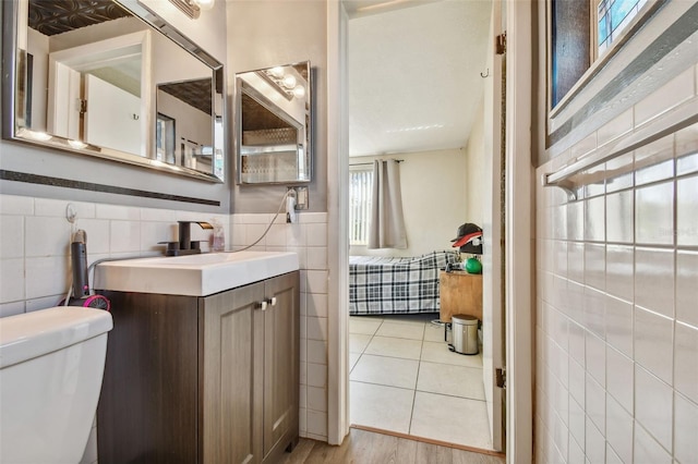 bathroom with wood-type flooring, toilet, tile walls, and vanity