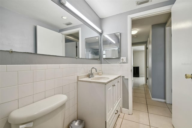 bathroom with tile patterned floors, vanity, tile walls, and toilet