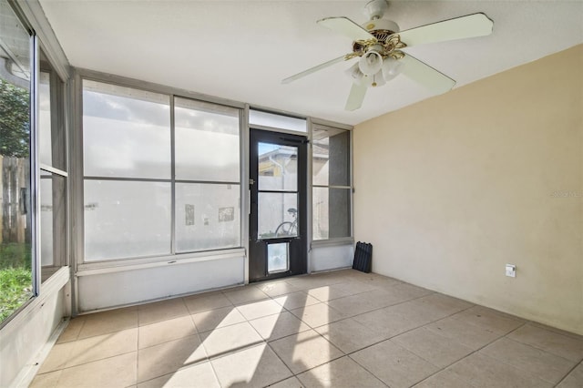 tiled spare room with expansive windows, ceiling fan, and a healthy amount of sunlight