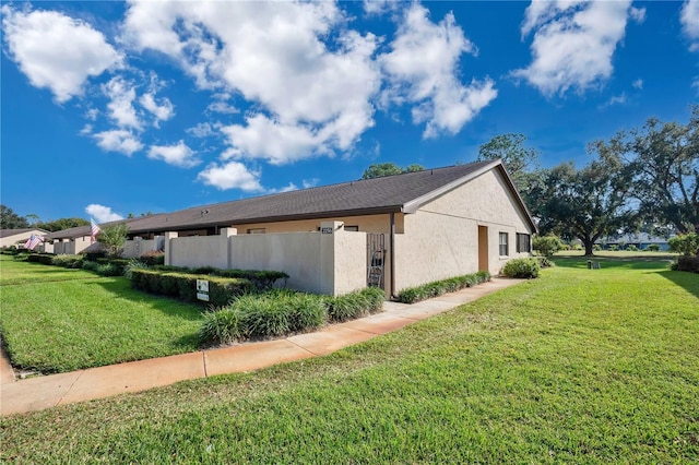 view of property exterior with a yard, fence, and stucco siding