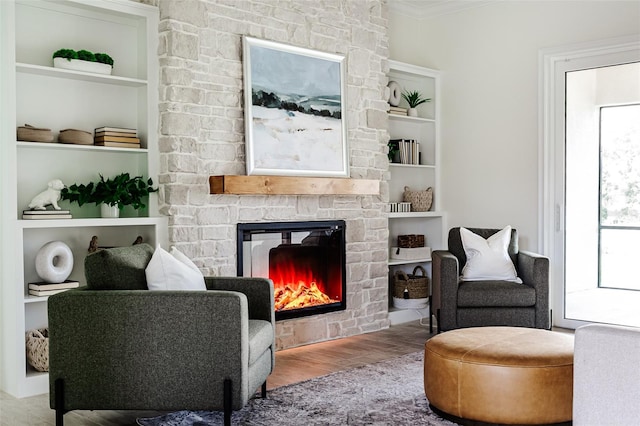 sitting room featuring crown molding, light hardwood / wood-style flooring, a fireplace, and built in shelves