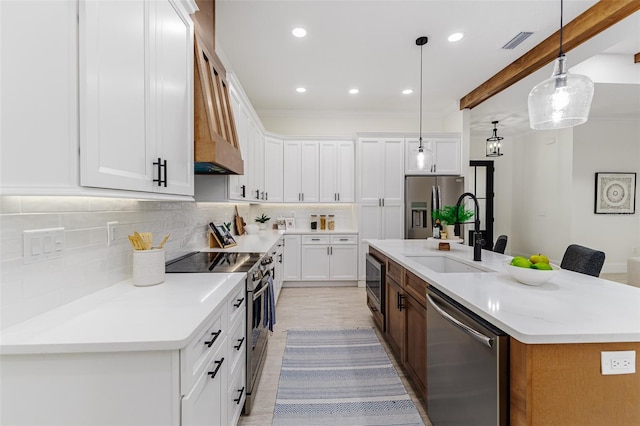 kitchen with stainless steel appliances, pendant lighting, an island with sink, and white cabinets