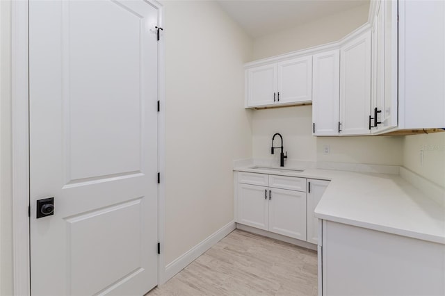 kitchen with white cabinetry, sink, and light wood-type flooring