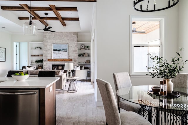 dining area featuring a fireplace, built in features, coffered ceiling, beam ceiling, and light hardwood / wood-style flooring