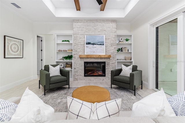 living room with beamed ceiling, ornamental molding, built in features, a fireplace, and light hardwood / wood-style floors