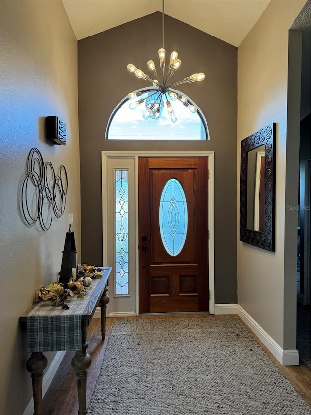 entrance foyer with baseboards, high vaulted ceiling, and a notable chandelier