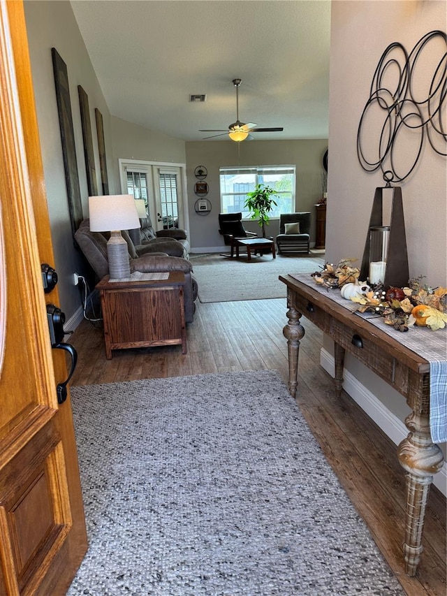 living room featuring visible vents, ceiling fan, baseboards, and wood finished floors