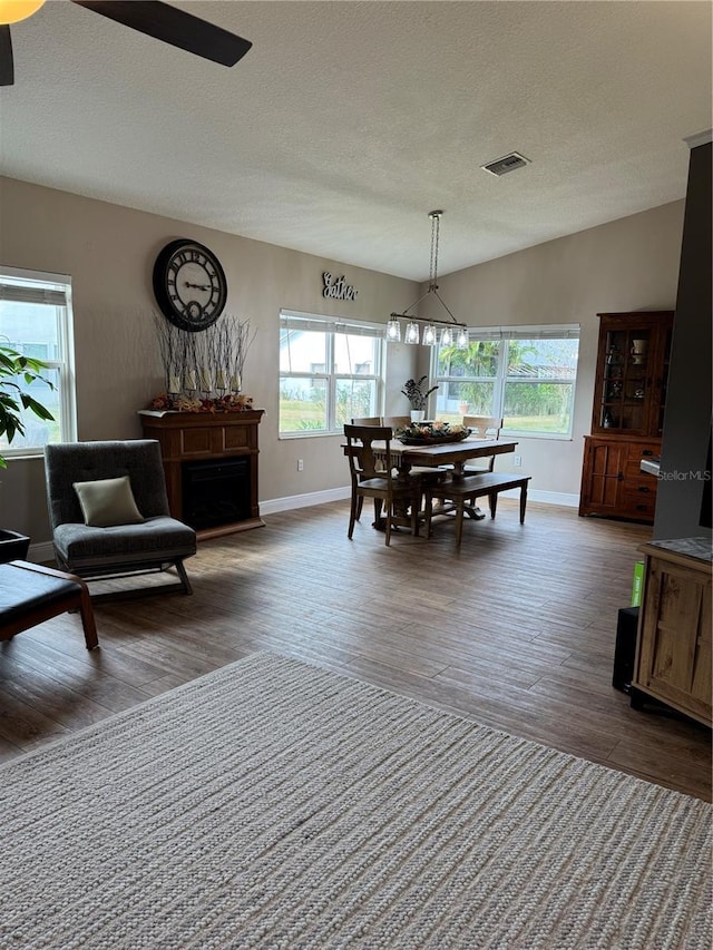 dining area featuring vaulted ceiling, plenty of natural light, wood finished floors, and visible vents