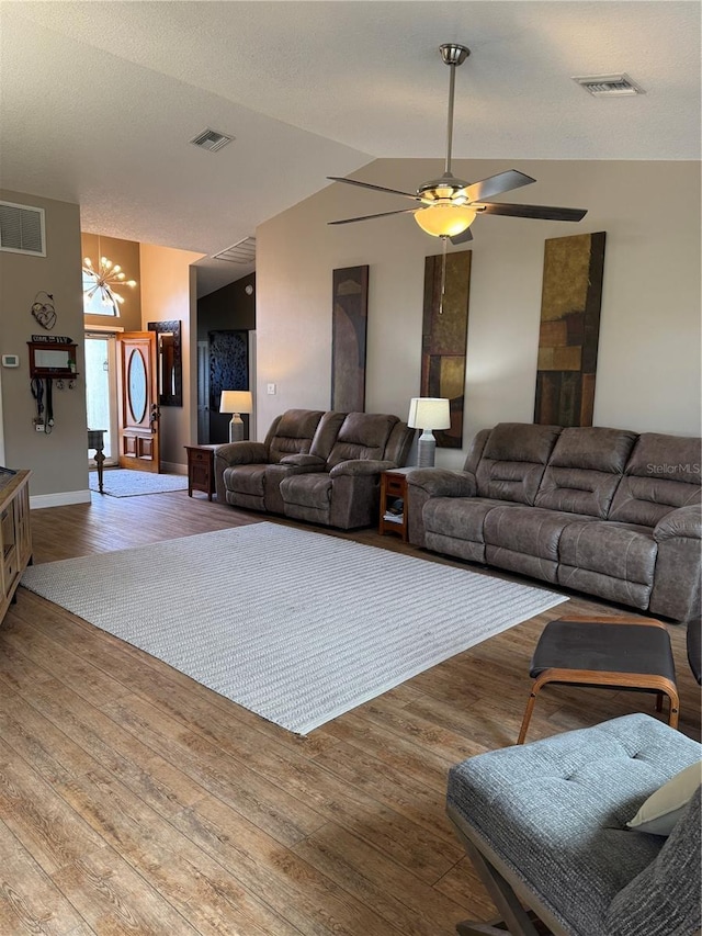 living area featuring lofted ceiling, wood finished floors, and visible vents