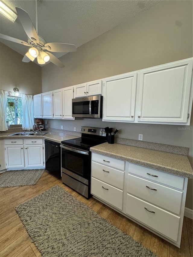 kitchen with white cabinetry, appliances with stainless steel finishes, vaulted ceiling, and a sink