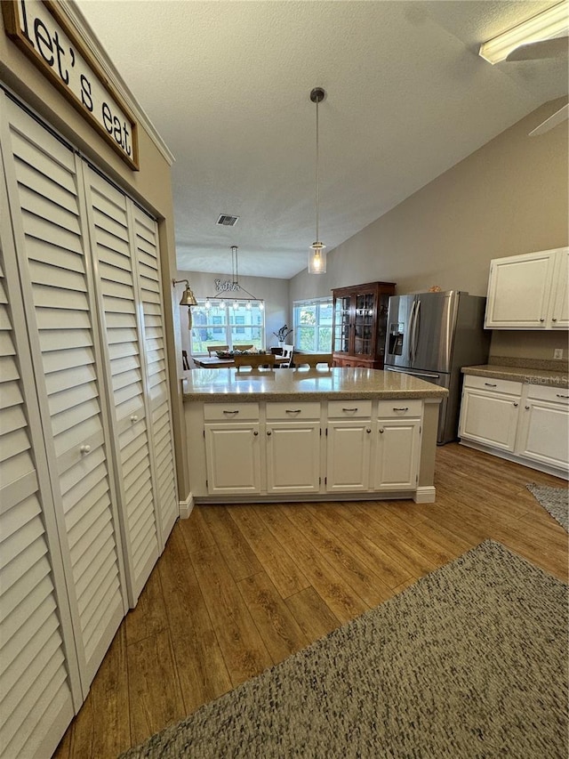 kitchen with white cabinets, stainless steel refrigerator with ice dispenser, and wood finished floors