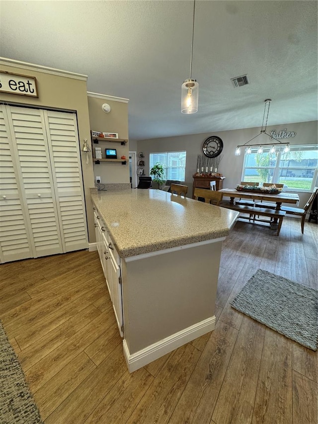 kitchen featuring pendant lighting, wood-type flooring, visible vents, and a textured ceiling