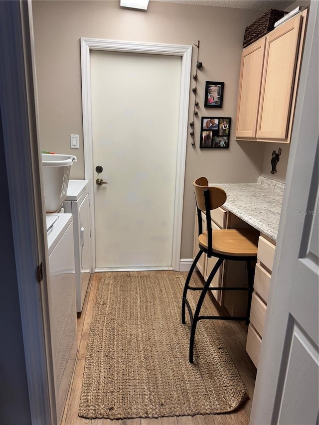 laundry area with cabinet space, light wood finished floors, and washing machine and clothes dryer