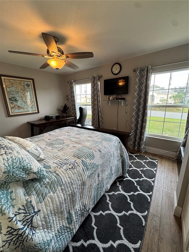 bedroom featuring wood-type flooring, ceiling fan, a textured ceiling, and baseboards