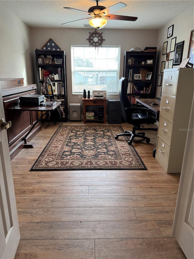 office space with ceiling fan, a textured ceiling, and wood finished floors