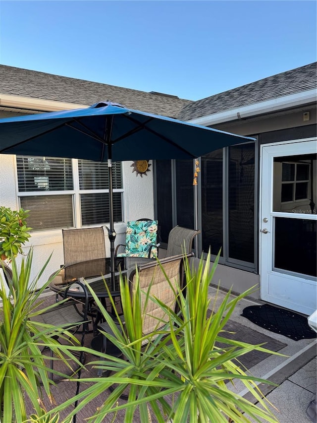 exterior space featuring stucco siding and roof with shingles