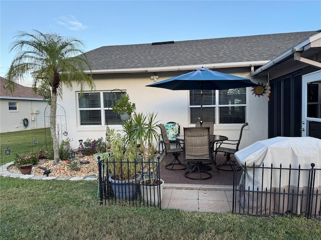 rear view of property featuring roof with shingles, fence, a patio, and stucco siding