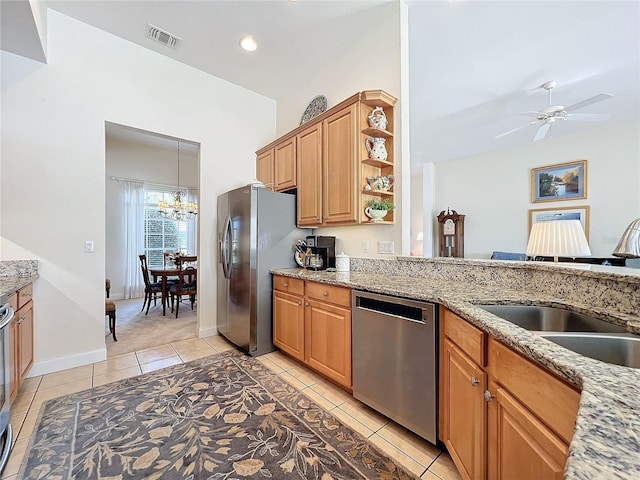 kitchen featuring stainless steel appliances, light stone countertops, sink, and ceiling fan with notable chandelier