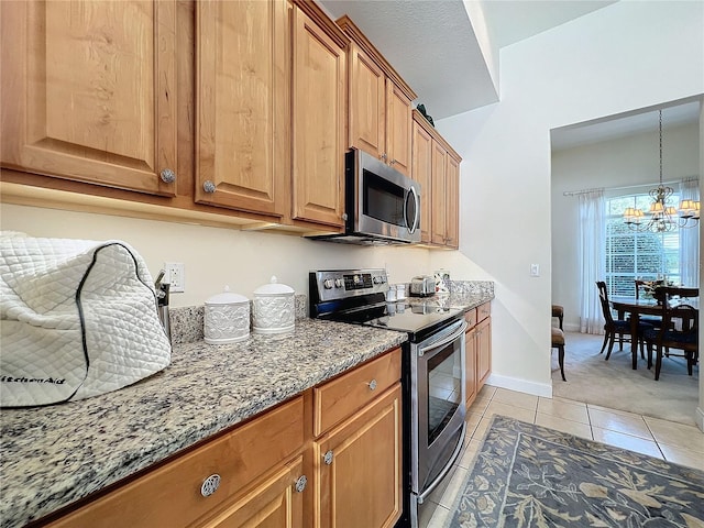 kitchen with stainless steel appliances, pendant lighting, an inviting chandelier, light tile patterned floors, and stone counters