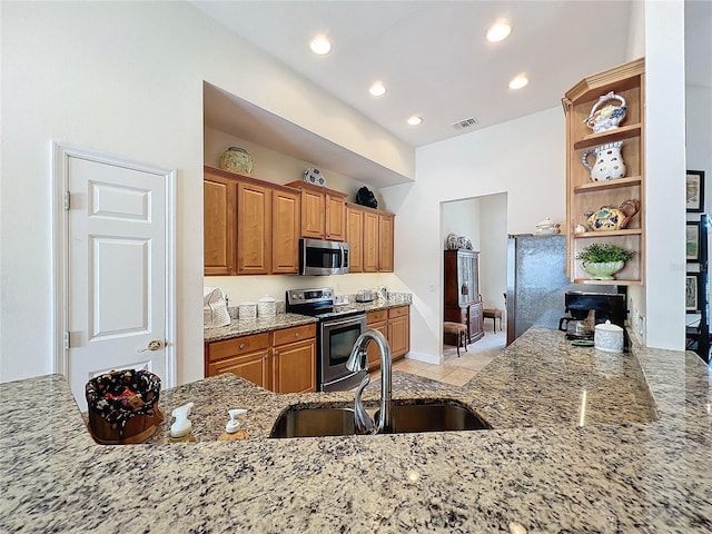 kitchen with light stone counters, appliances with stainless steel finishes, sink, and light tile patterned floors