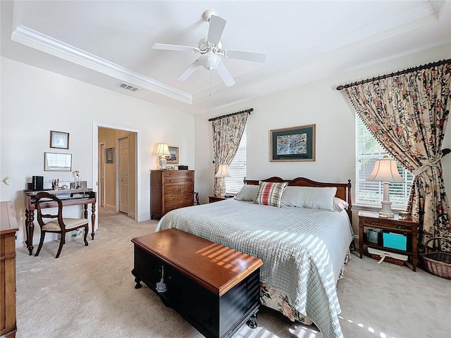 bedroom featuring ornamental molding, a tray ceiling, light colored carpet, and ceiling fan