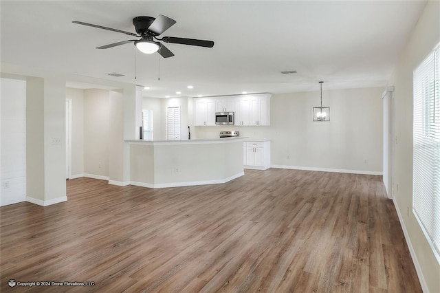 unfurnished living room with light hardwood / wood-style flooring and ceiling fan with notable chandelier