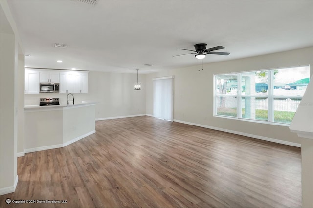 unfurnished living room featuring ceiling fan, sink, and wood-type flooring