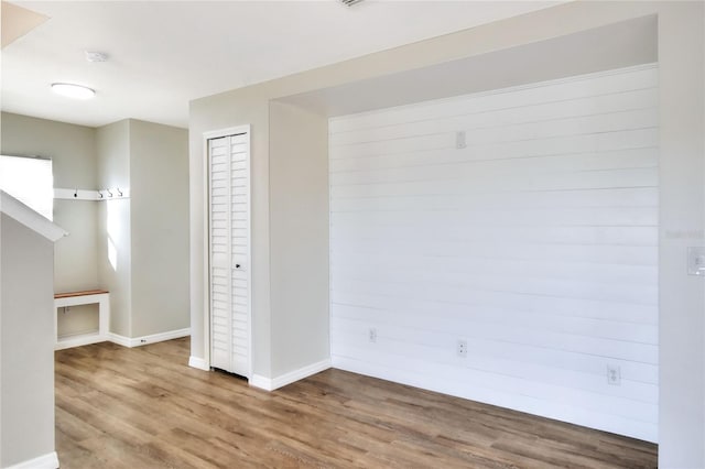 interior space with wood walls, a closet, and wood-type flooring