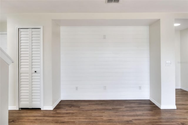 interior space with dark wood-type flooring and wooden walls