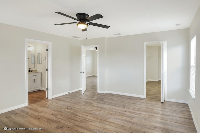 unfurnished bedroom featuring a closet, a spacious closet, light hardwood / wood-style flooring, and ensuite bath