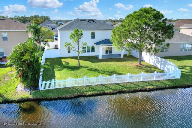 back of property with a water view and a yard