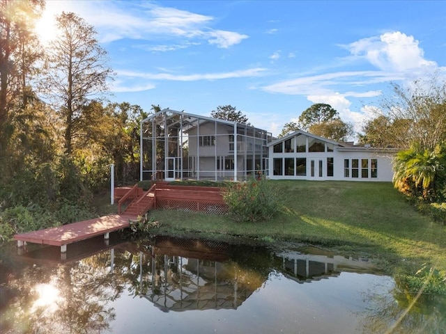 rear view of house featuring a water view, glass enclosure, and a lawn