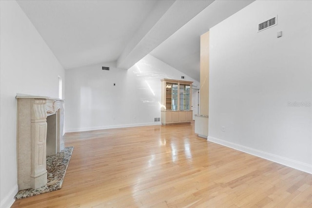 unfurnished living room featuring lofted ceiling with beams and light hardwood / wood-style floors