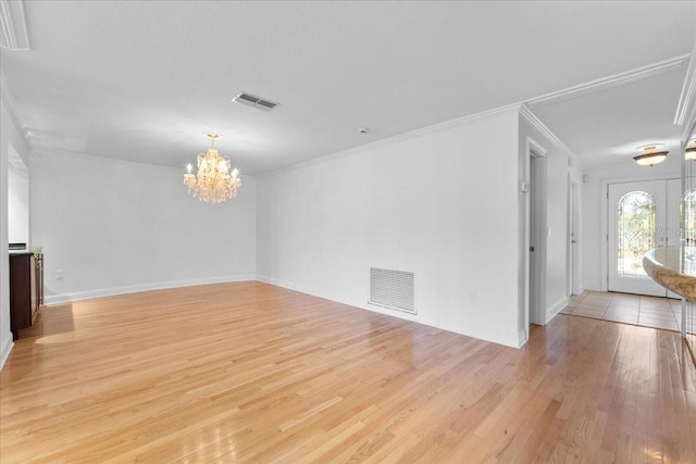 unfurnished room with french doors, light hardwood / wood-style floors, an inviting chandelier, and crown molding