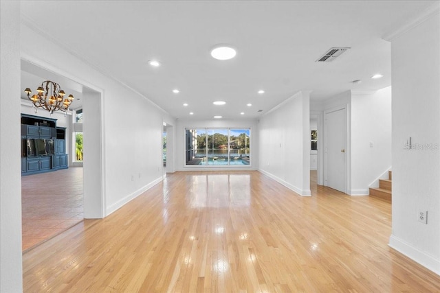 unfurnished living room with light wood-type flooring, crown molding, and a notable chandelier