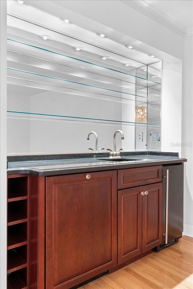 bar featuring stainless steel fridge, crown molding, and light wood-type flooring