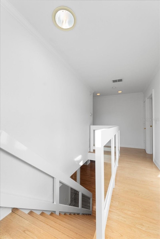 stairs with wood-type flooring and crown molding