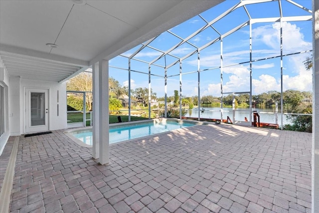 view of pool featuring glass enclosure, a patio area, and a water view