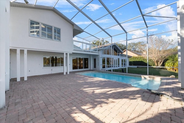 view of pool with glass enclosure and a patio