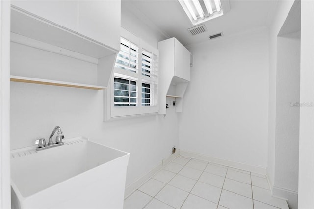 laundry room featuring electric dryer hookup, cabinets, light tile patterned floors, and sink