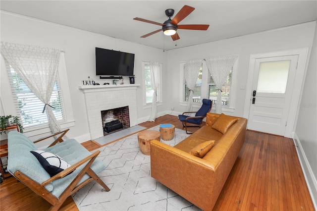 living room with ceiling fan, a fireplace, light hardwood / wood-style floors, and plenty of natural light