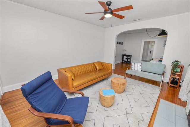 living room with crown molding, wood-type flooring, and ceiling fan