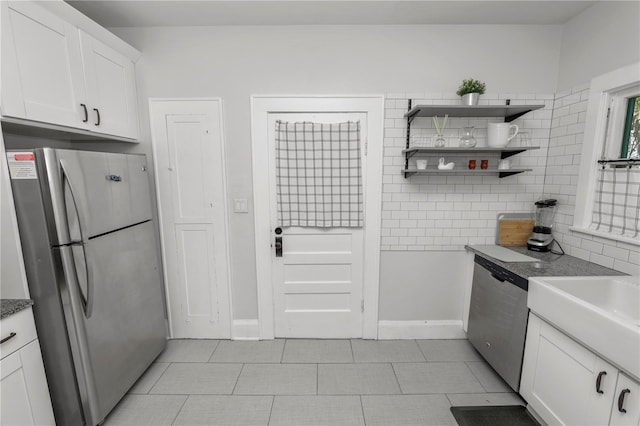 kitchen with appliances with stainless steel finishes, white cabinetry, and light tile patterned floors