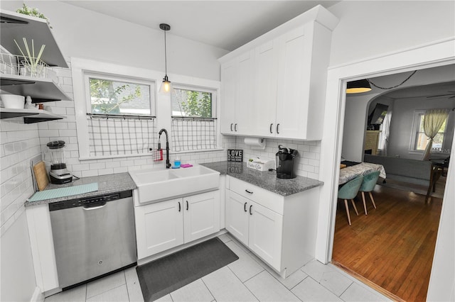 kitchen with decorative backsplash, light hardwood / wood-style flooring, sink, stainless steel dishwasher, and white cabinetry