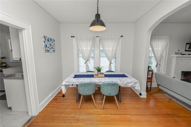 dining area with light hardwood / wood-style flooring and a brick fireplace