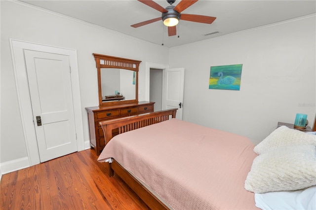 bedroom featuring hardwood / wood-style floors, crown molding, and ceiling fan