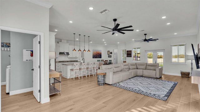 living room with ceiling fan, sink, light hardwood / wood-style flooring, and french doors