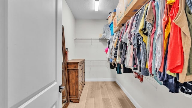 walk in closet with light hardwood / wood-style flooring